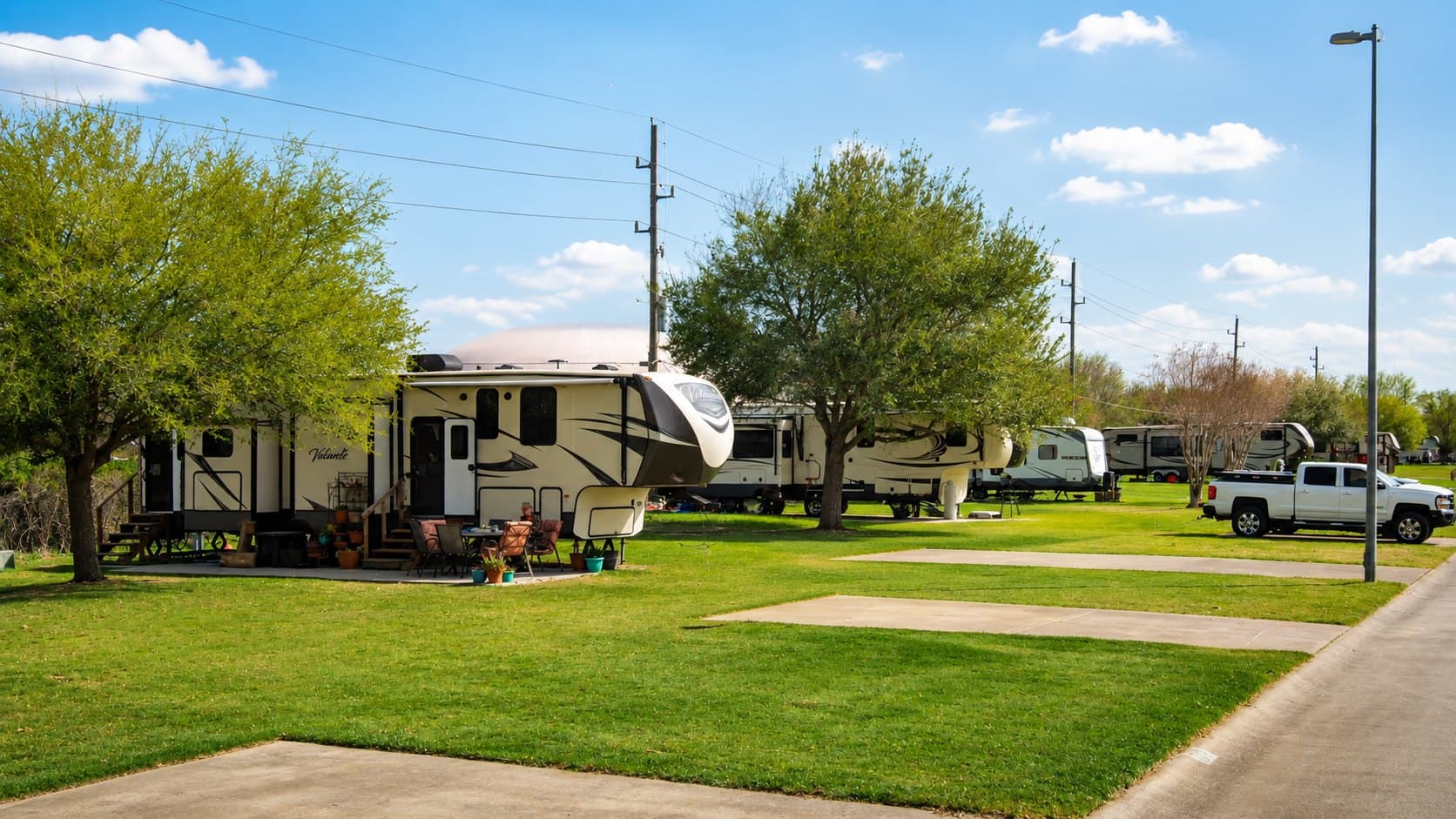 RV with an awning parked on a grass site beside a pickup truck at Briarwood Estates